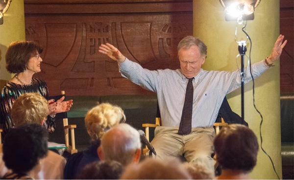 Harriet with Dick arms raised sitting before the audience.