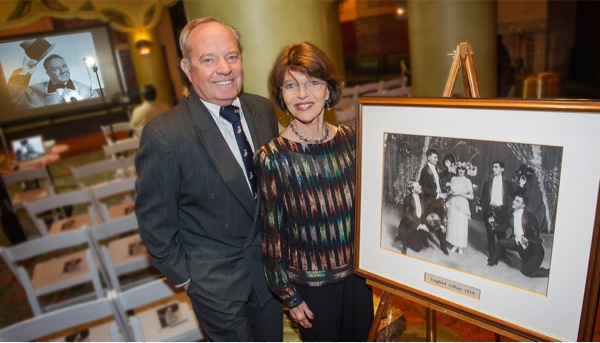 Ron and Harriet standing next to a framed black and white photo.