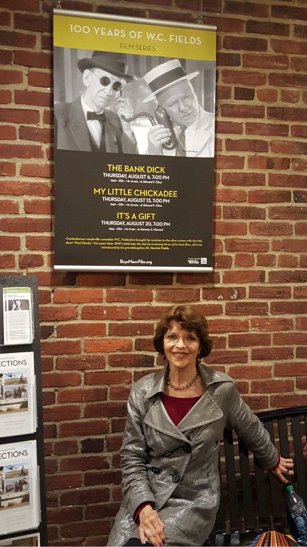 Dr. Harriet Fields sitting next to poster. Dr. Harriet Fields sitting in front of 100 years of W.C. Fields poster.