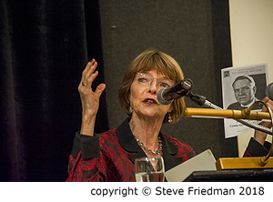 Candid photo of Dr. Harriet Fields sitting and speaking into the microphone while holding up a picture of her grandfather.
